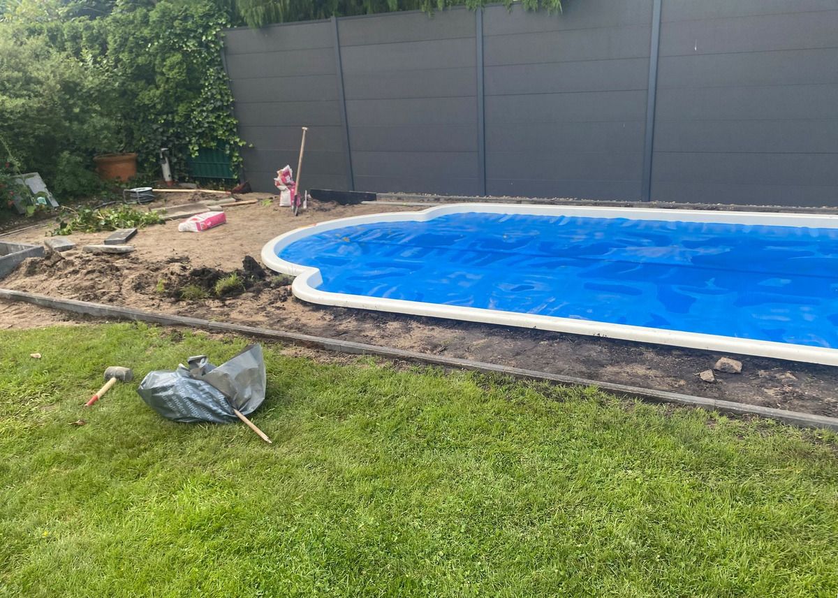 Baustelle: das Schwimmbecken liegt frei, ringsum aufgeschütteter Sand und Werkzeug