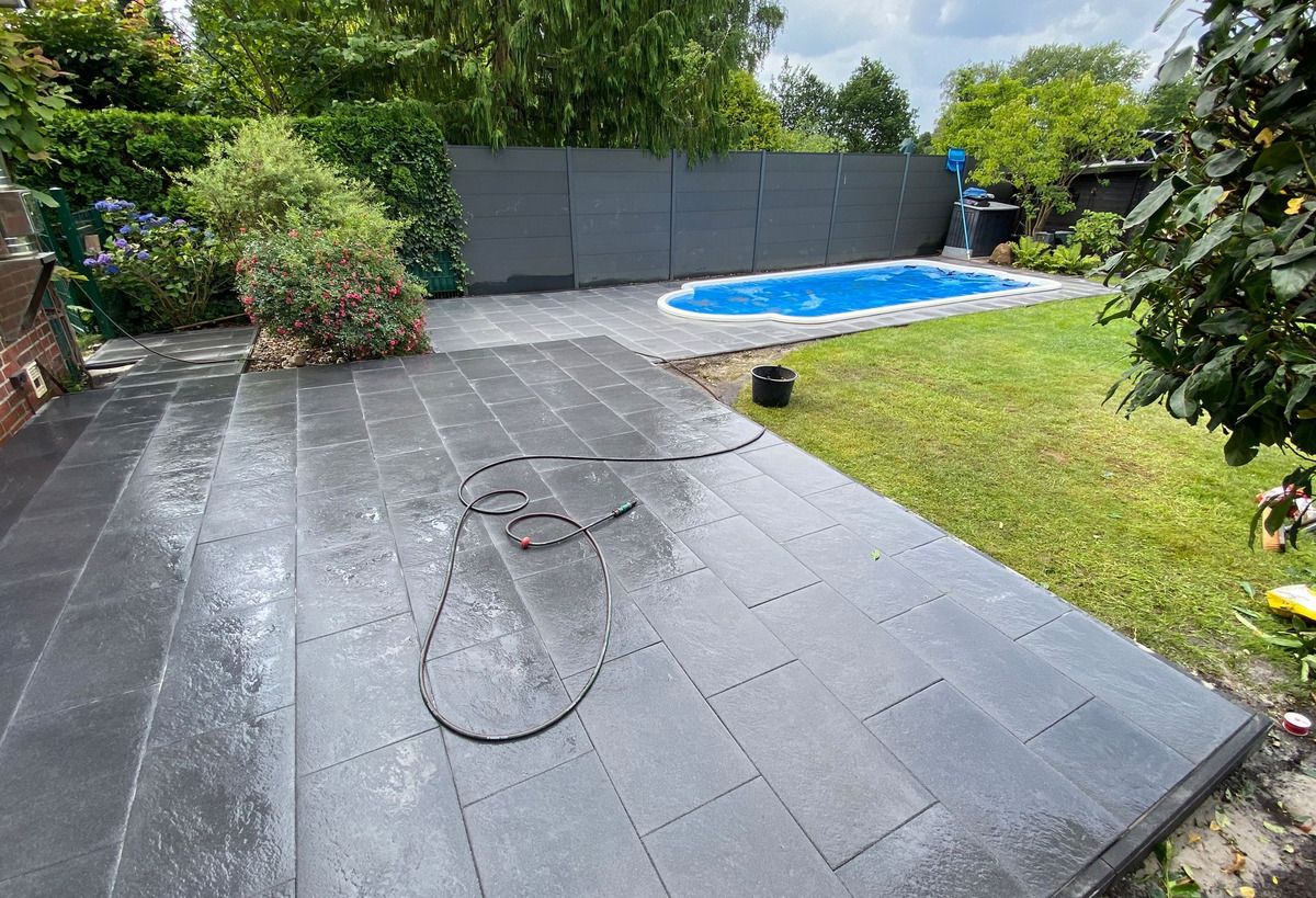 Fertige Terrasse aus großformatigen anthrazitfarbenen Platten neben einem Pool