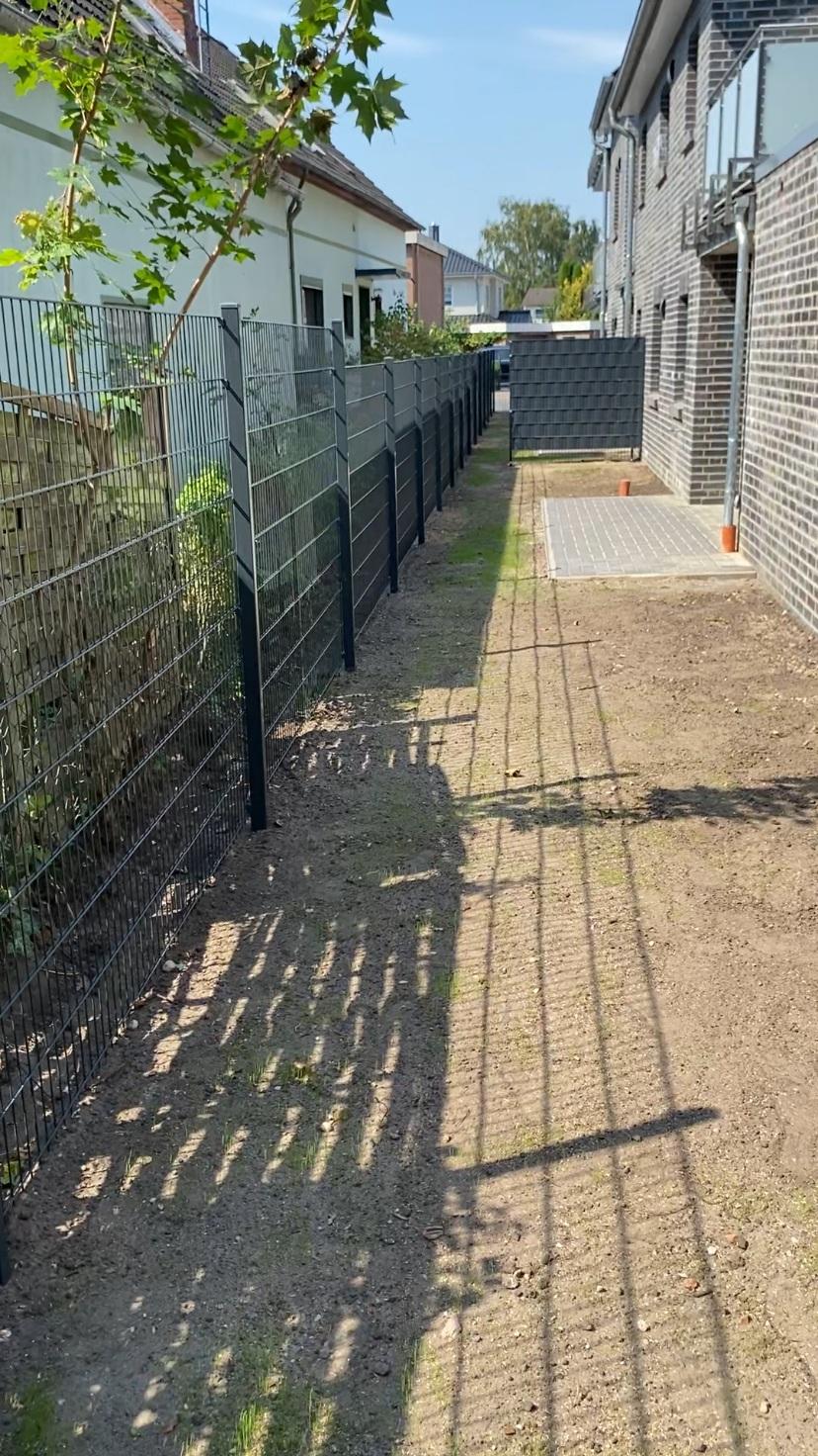 Doppelstabmattenzaun mit Sichtschutzstreifen zwischen zwei Wohnhäusern