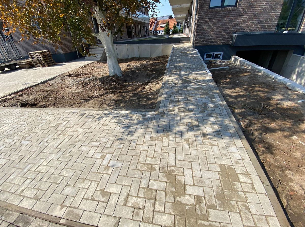 Neu verlegter Pflasterweg im Fischgrätverband entlang eines Wohnhauses